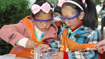 Two little girl wearing pink head bands and safety goggles working on a science experiment Two little girl wearing pink head bands and safety goggles working on a science experiment