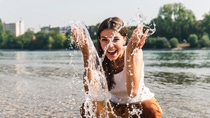 Carefree young woman refreshing in water of a river