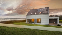暴风雨般的乌云聚集在一座白色的现代房子上,房前有一片绿色的小草坪和太阳能屋顶板,毗邻海滩,离汹涌的海浪仅几米之遥。 暴风雨般的乌云聚集在一座白色的现代房子上,房前有一片绿色的小草坪和太阳能屋顶板,毗邻海滩,离汹涌的海浪仅几米之遥。