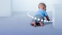 Cute baby with graphic circles around crawling towards white block 