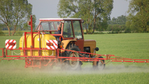 Red and yellow fertilizing tractor in a field  