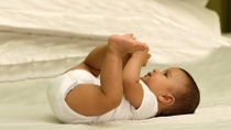A happy baby wearing a diaper is lying on its back. A happy baby wearing a diaper is lying on its back.
