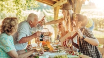 Cheerful women and men sitting around a table full of food and celebrating. Cheerful women and men sitting around a table full of food and celebrating.
