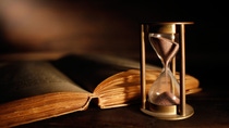 old hourglass and antique book with open pages old hourglass and antique book with open pages