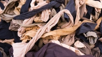 Close-up of a large pile of waste textile pieces in various colors, tangled together. Close-up of a large pile of waste textile pieces in various colors, tangled together.