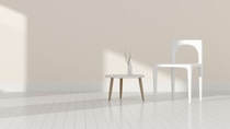 White chair and white side table with vase in a bright room.