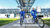 Twee medewerkers fietsen over het buitenterrein bij BASF Heerenveen Twee medewerkers fietsen over het buitenterrein bij BASF Heerenveen