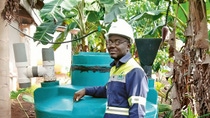 Enoch Kofi Boadu is leaning against a Biogas machine with his arm propped up on it
