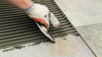 Laying Ceramic Tiles. Troweling mortar onto a concrete floor in preparation for laying white floor tile. Laying Ceramic Tiles. Troweling mortar onto a concrete floor in preparation for laying white floor tile.