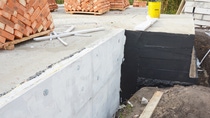 Waterproofing house foundation with  bitumen and styrofoam rigid foam insulation against water leaking.