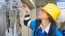 female engineer with yellow hard hat and protective glasses looking at face covering female engineer with yellow hard hat and protective glasses looking at face covering