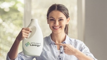 Beautiful young woman is holding a fabric softener over the basin with laundry, showing Ok sign, looking at camera and smiling; Shutterstock ID 510915580; Thema: Laundry