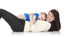 Happy woman laying down holding cute/happy baby laying on her chest 
