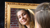 Blonde woman looking at herself in the mirror with gold frame