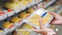 A person is holding a plastic package of sliced cheese in a grocery store. The background features shelves stocked with various types of cheese. A person is holding a plastic package of sliced cheese in a grocery store. The background features shelves stocked with various types of cheese.