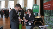 Man and woman in a suit at a BASF sustainability conference. Woman holding booklet explaining "Palm Dialog Time for change" 