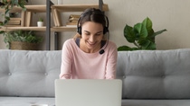 Smiling young woman student wear wireless headset using laptop for e learning course online teaching in internet, happy female teacher tutor communicating by video conference call sit on sofa at home Smiling young woman student wear wireless headset using laptop for e learning course online teaching in internet, happy female teacher tutor communicating by video conference call sit on sofa at home