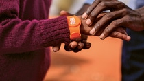 Im Fokus stehen zwei Hände. Um einem Arm ist ein Tap2Eat-Armband umgelegt. Im Fokus stehen zwei Hände. Um einem Arm ist ein Tap2Eat-Armband umgelegt.