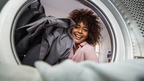 Young black African American woman holding a basket of clothes to be washed in a automatic laundry