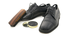 Black dress show with shoe polish and a brush 