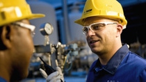Two employees in discussion wearing yellow hard hat and safety goggles