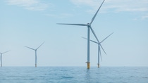 View from above over several wind turbines standing in a calm sea