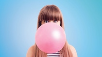 Woman blows bubble gum bubble in front of her face Woman blows bubble gum bubble in front of her face