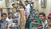 Doctors and patients sit together in a trolley and share food.