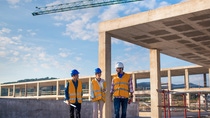 Three people standing in front of a construction site. Three people standing in front of a construction site.