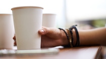 Female hand holding disposable cu of coffee