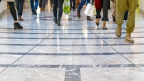 A modern floor with legs of a crowd walking in a shopping mall in the background A modern floor with legs of a crowd walking in a shopping mall in the background