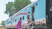 Two people board a colorfully painted train. It is the mobile hospital.