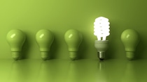 Five green light bulbs lined up against a green background, with the fourth bulb being a lit.