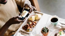 Einen Person macht mit einem Smartphone ein Bild von seinem Essen.