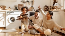 happy multi ethnic family: little boy laughing and playing with   toy airplane in front of his  his parents in the kitchen at home