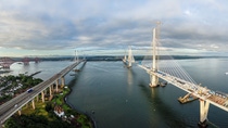 The new Queensferry Crossing bridge (on the right) under construction over the Firth of Forth with the older Forth Road bridge (on the left) and with the iconic Forth Rail Bridge in the far left. The new Queensferry Crossing bridge (on the right) under construction over the Firth of Forth with the older Forth Road bridge (on the left) and with the iconic Forth Rail Bridge in the far left.
