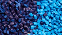 Close up of a two stacks of blue plastic polypropylene granules on a table.