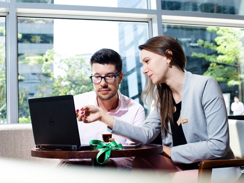 Ein Mann und eine Frau im Anzug schauen gemeinsam auf einen Laptopbildschirm