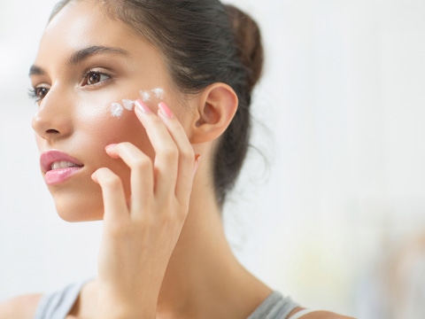 Woman applying moisturizer to cheek