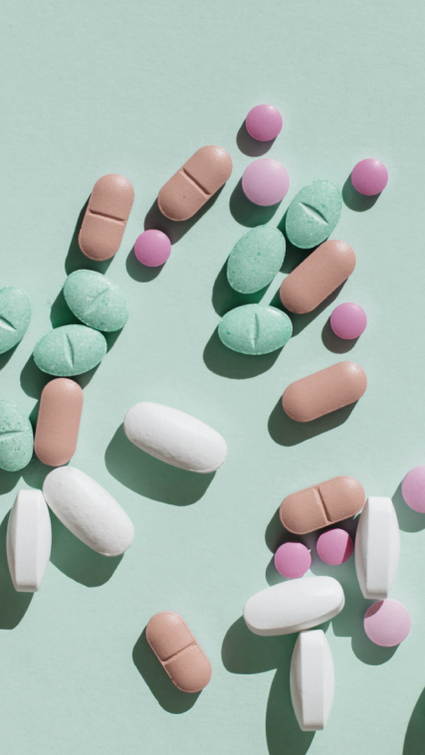 Many colourful pills scattered on a green surface.