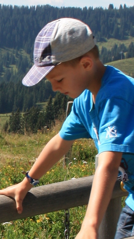Two little boys holding ledge looking down surrounded by trees and mountains Two little boys holding ledge looking down surrounded by trees and mountains
