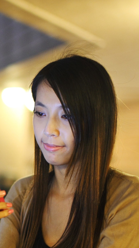 Woman standing at a train station looking at her phone with red phone cover Woman standing at a train station looking at her phone with red phone cover