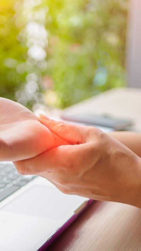 Closeup woman holding her painful hand from using computer. Office syndrome hand pain by occupational disease. Closeup woman holding her painful hand from using computer. Office syndrome hand pain by occupational disease.