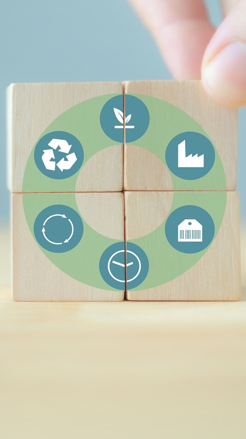 Four wooden blocks form a circular graphic with icons for recycling, sustainability, and production; a hand is aligning the blocks. Four wooden blocks form a circular graphic with icons for recycling, sustainability, and production; a hand is aligning the blocks.