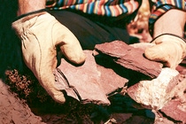 Zwei Hände halten mehrerer Schiefer über die Erde.