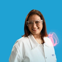 A BASF employee from India standing in a white lab coat against a blue background, a light swirl hovers around the shoulder. A BASF employee from India standing in a white lab coat against a blue background, a light swirl hovers around the shoulder.