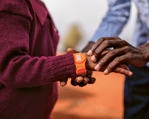 Im Fokus stehen zwei Hände. Um einem Arm ist ein Tap2Eat-Armband umgelegt.